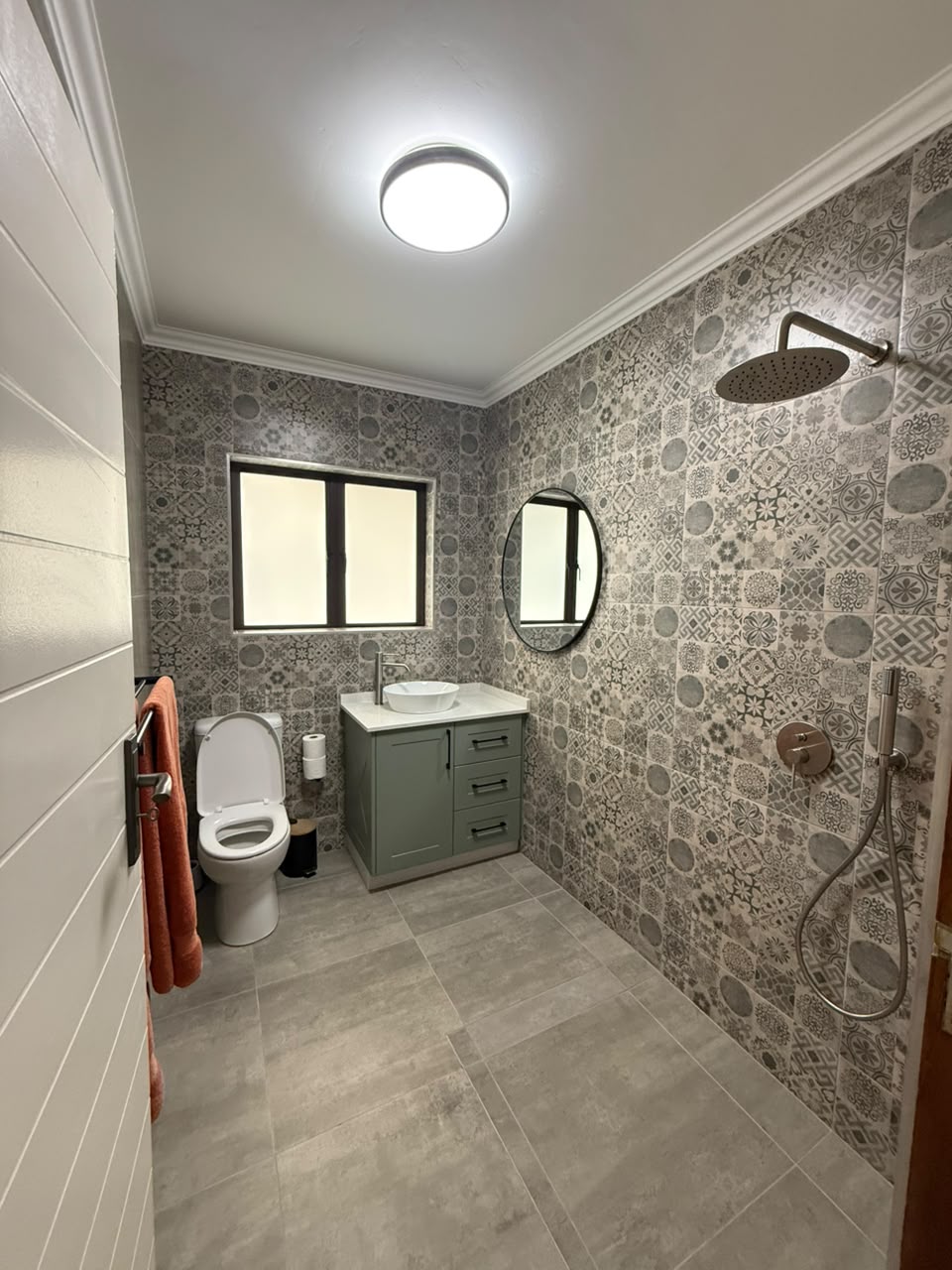 Finished bathroom renovation with patterned tiles, vanity and walk-in rain shower